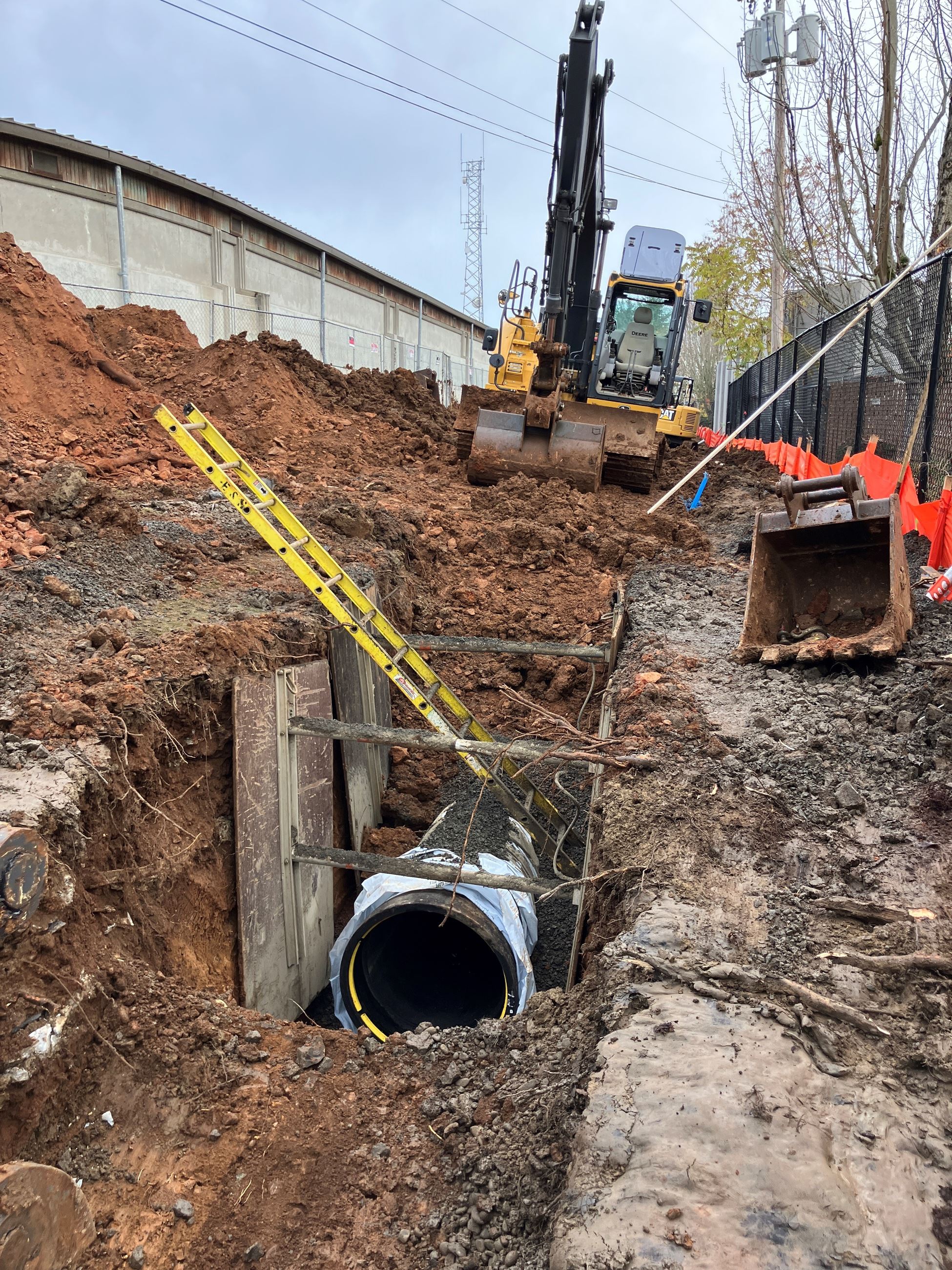a large water main pipe lying in a dirt trench. 